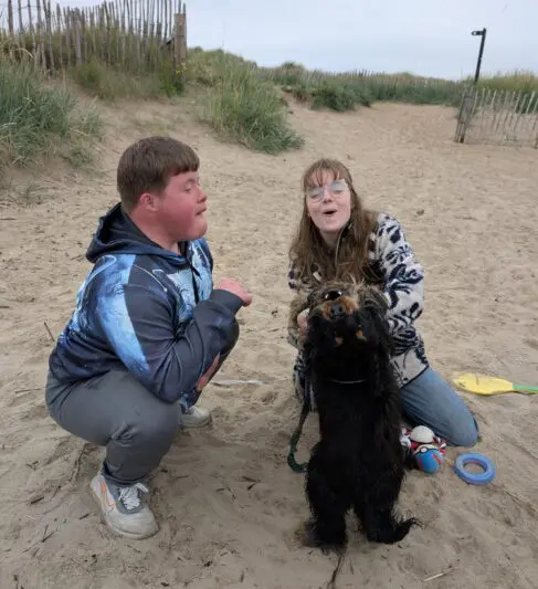 Two people singing with a dog at the beach